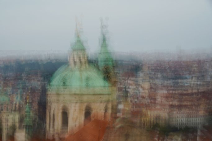 Prag 1 Unscharfe Ansicht von zwei grünen Kuppeln eines historischen Gebäudes in der Ferne.