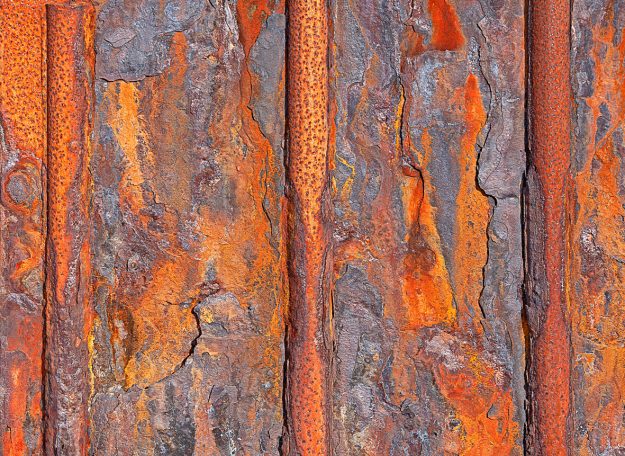 Rost 11 Rostige Holzoberfläche mit roten und orangen Farbtönen und strukturierten Furchen.