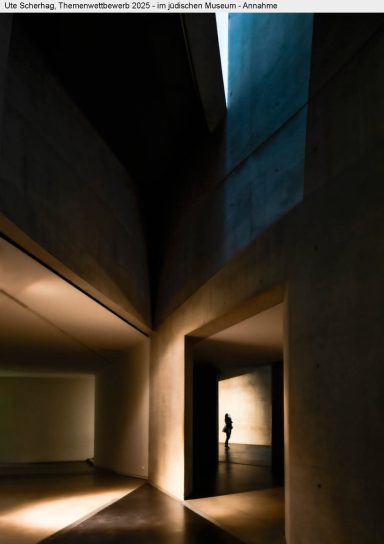 Ute Scherhag - Annahme Dunkler Raum mit geometrischen Wänden und schmalem Lichtstrahl, silhouettierte Person.
