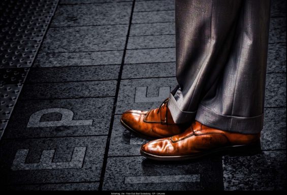 Ute Scherhag. - Urkunde Elegante braune Schuhe stehen auf einem Gehweg mit Markierungen.